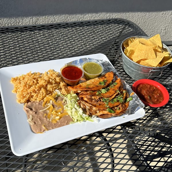 Tulum Fresh Mexican Grill's birria tacos with rice, beans, salsa, and a bucket of tortilla chips.